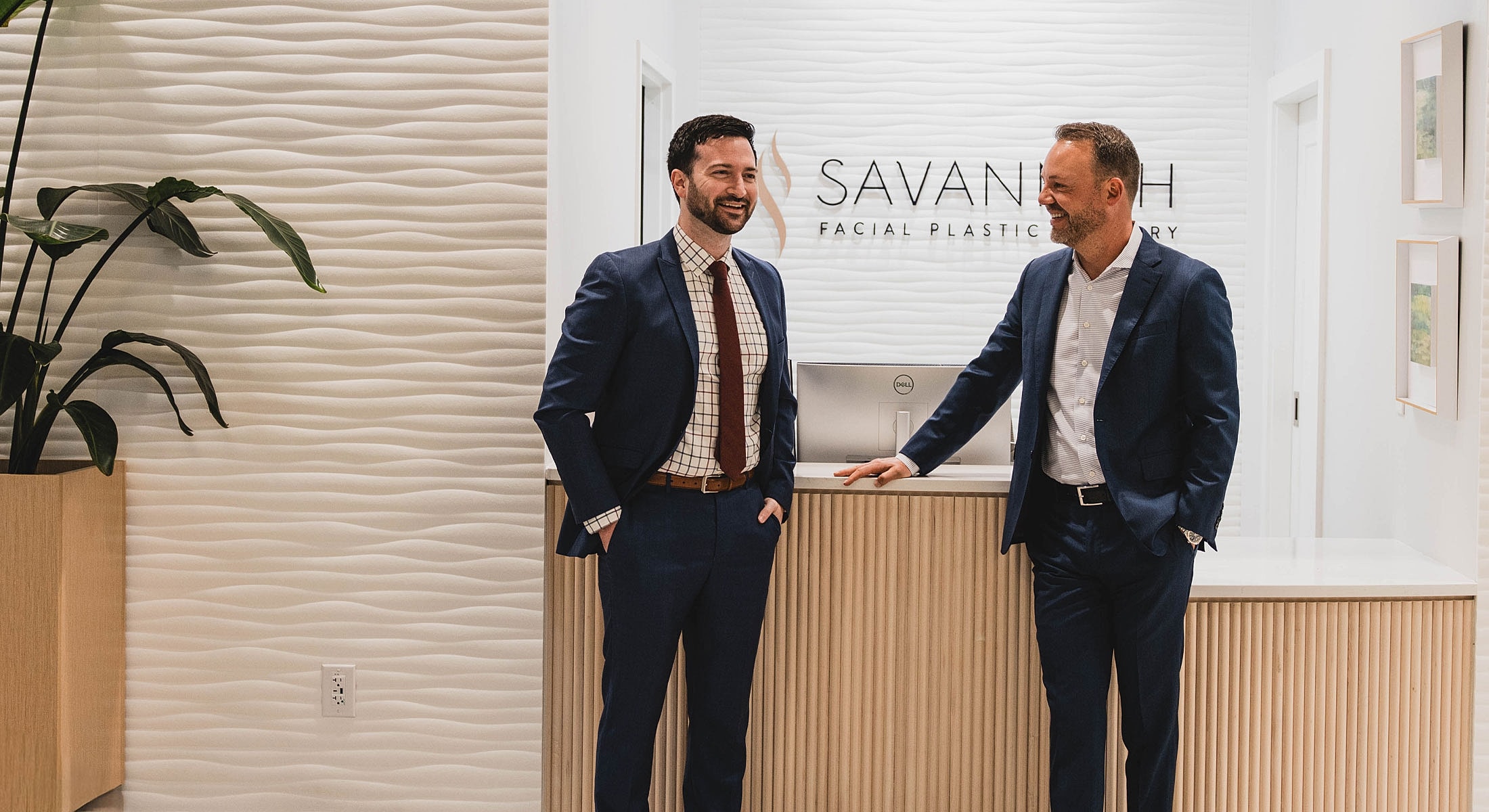 Two men in suits at a reception area.